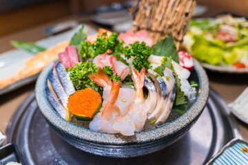 Close-up of Japanese sushi and sashimi food. Maki ands rolls with tuna, salmon, and fish egg. Top view of assorted sushi. Side view of assorted sashimi with tuna, salmon, shrimp, fish egg. 