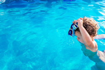 Baby girl playing in the pool with a plastic toy in summer in the sun with copy space.