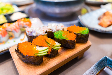 Close-up of Japanese sushi and sashimi food. Maki ands rolls with tuna, salmon, and fish egg. Top view of assorted sushi. Side view of assorted sashimi with tuna, salmon, shrimp, fish egg. 