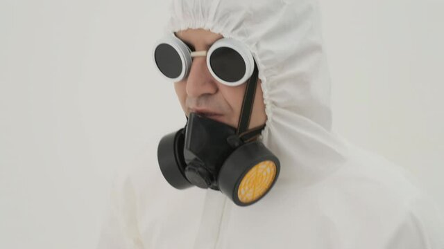 Man in white chemical protection suit enters the frame. White background, slow motion
