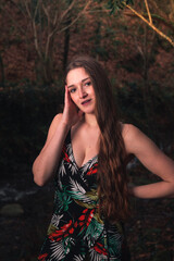 Young caucasian woman with a colorful dress in the middle of the forest next to a little river