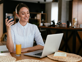 Beautiful woman drinking coffee and having video call. Young girl enjoying in morning coffee
