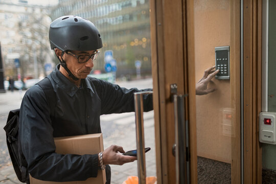 Bicycle courier pressing intercom button