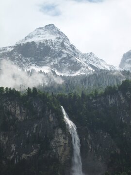 Oltschibach waterfall and snow-covered peak behind Unterbach airfield near Meringen, Switzerland