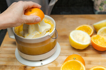 woman's hand making orange and lemon juice with an electric juicer