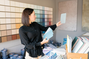 Young woman choosing materials for home renovation. interior designer looking at color samples for wal. House renovation concept - obrazy, fototapety, plakaty