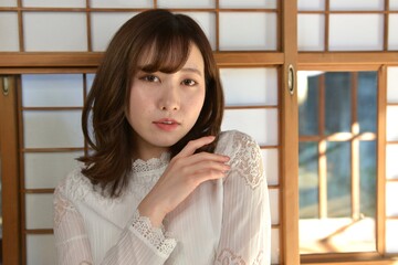 古民家の和室で微笑む白いワンピースの美しい女性	