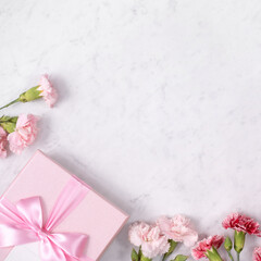 Concept of Mother's day holiday greeting gift with carnation bouquet on white marble background