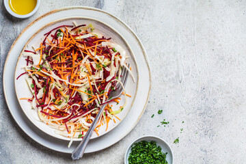 Chopped beetroot, carrot, cabbage salad with oil and herbs, gray background. Healthy food concept.