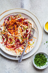 Beetroot, carrot, cabbage salad with oil and herbs, gray background. Healthy food concept.