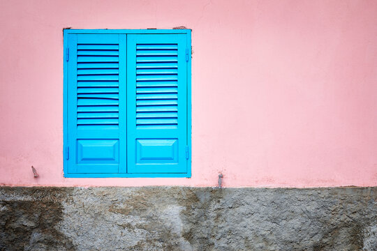 Pink wall with blue window shutter