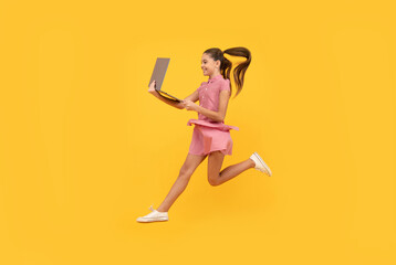 teenage girl jumping with laptop. child jump with notebook. happy kid play computer game.