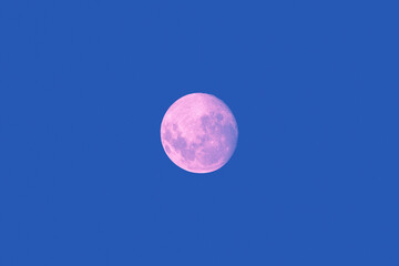 Full super moon glowing against blue sky dark background
