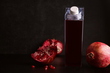 Mock up bottles with pomegranate juice on a black background. Next ingredient is fresh pomegranate. Copy space