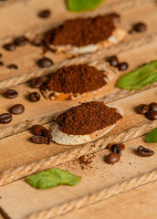 Close up view of some fresh ground and beans coffee on a wood basket with green leaves barista setup