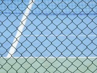 Fototapeta premium green wire mesh of fence enclose the tennis court