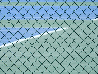 green wire mesh of fence enclose the tennis court