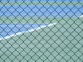 green wire mesh of fence enclose the tennis court