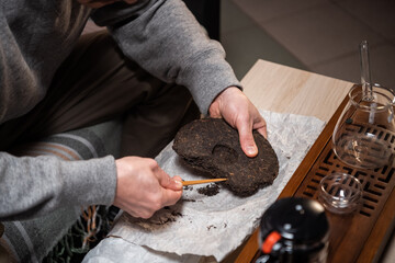Shot without a face. Close-up of the master's hands picking a tea cake with a needle for a tea ceremony or chinese tea tasting