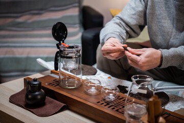 A novice in the art of traditional chinese tea drinking conducts a tea ceremony at home. Puts pu erh tea in the teapot