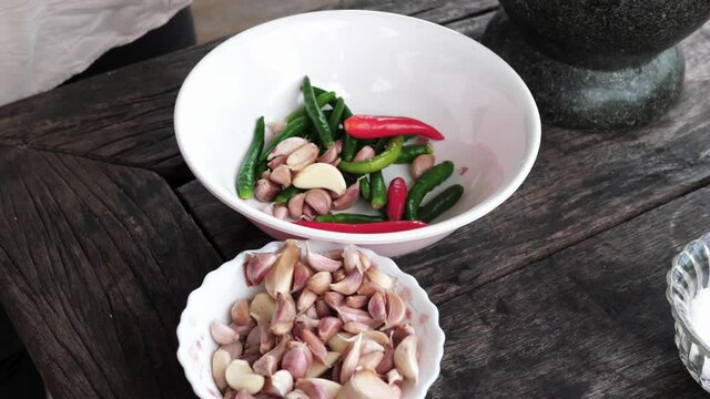 Female hand putting garlic into a bowl full of spices on a wooden table - cook preparation