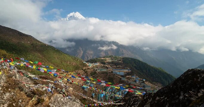 Motion time lapse of clouds moving above the famous Namche Bazar village on the way to the Everest base camp trek in the Himalaya in Nepal with Tibetan Buddhism prayer flags