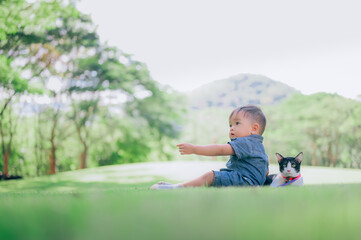 Cute boy with a kitten lying in the grass,portrait of baby with  with his cat,pet