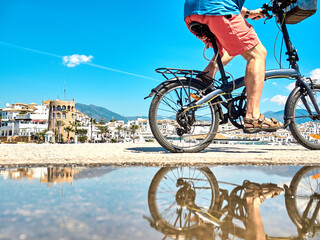 Cyclist rides next to puddle which is reflected