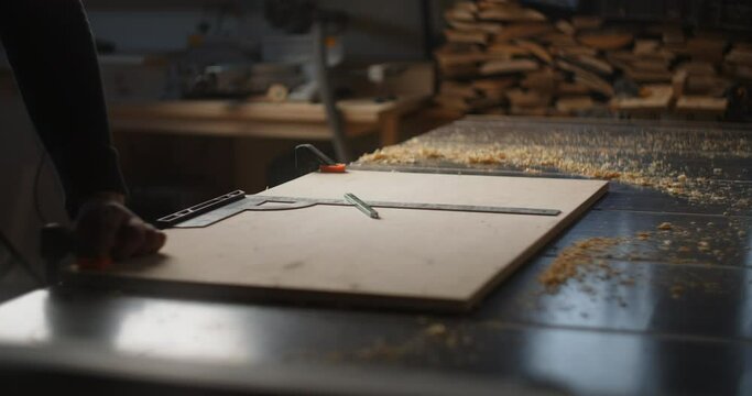 Carpenter marks out a plywood block before cutting it, furniture manufacturing, woodworking at craftsman's workshop, 4k 60p Prores 422 HQ 10 bit