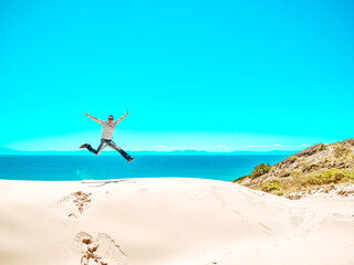 Fototapeta na wymiar man jumps on the Sand dune of Bolonia beach, province Cadiz, Andalucia, Spain