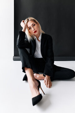 Fashion portrait of sensual trendy woman posing sitting on floor on white studio background