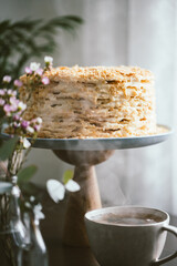 Homemade multilayers cake Napoleon on the cake stand and cup of tea.