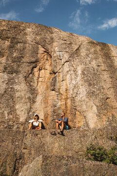 Low angle view of couple sitting on rock