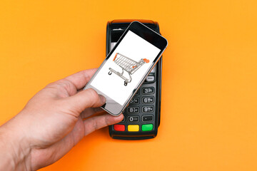 Terminal for paying for goods and telephone. The client holds a smartphone to make a purchase....
