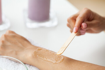 Obraz na płótnie Canvas Master does epilation of hands with help of sugar paste hot wax in salon beauty