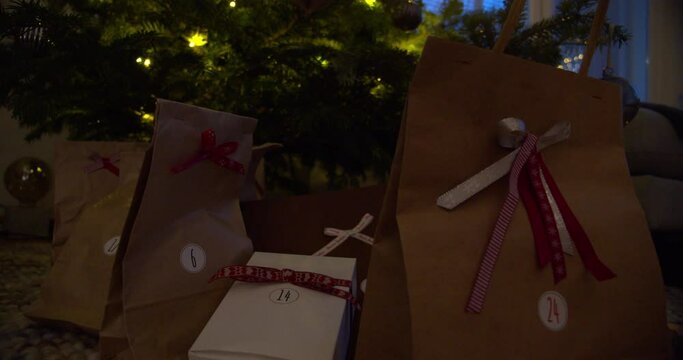 Presents under the Christmas tree in brown paper bags decorated with ribbon bows