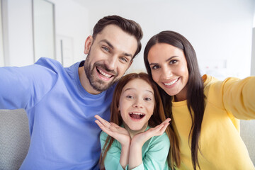 Fototapeta premium Photo of young happy family small girl mother father take selfie together smile good mood inside home living-room