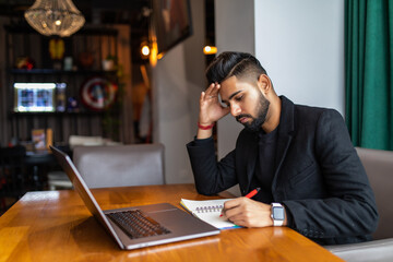 Fototapeta na wymiar Young indian man working on laptop at cafe shop