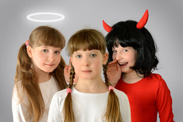 Angel and a Demon whisper in the kid child ear advice good and evil concept photography