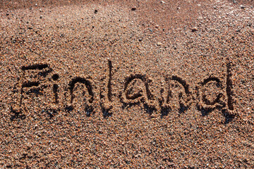 Word Finland handwritten on a sandy beach