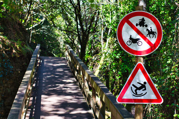 Pasarela el la ruta de fluvial de Sistelo. Señal de prohibición de quads, motocicletas y caballos. También señal de advertencia de suelo resbaladizo