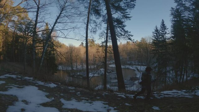 Happy woman practices Nordic walking in early spring forest. Healthy lifestyle, prevention of cardiovascular diseases, during pandemic isolation.
