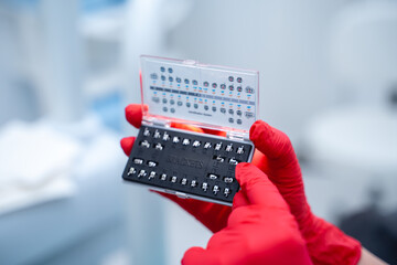 Dentist in latex gloves neatly and sterilely shows the patient braces