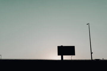 Empty billboard on top of bridge with a lone lamp post. 