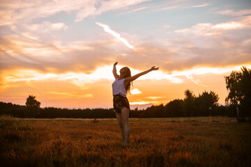 A beautiful girl on the field at sunset time, runs and laughs. Unity with nature, woman in the forest on the field.