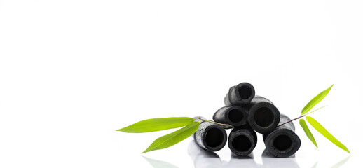 Bamboo activated charcoal sticks and green leaf isolated on white background.