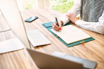 Close-up shot of businesswoman's hand while making notes into her binder
