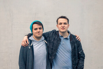 Portrait of two young people man watching the camera and embracing themselves arms on shoulders...