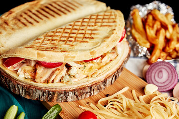 closed pizza on a wooden board with grated cheese and vegetables