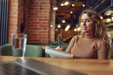 Student looking at computer screen and taking notes